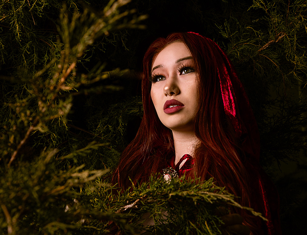 Ethnic looking girl with red hair and red lipstick wearing red velvet cape in the trees. Alyssa Bryn Photography. Bryssa. Bryssa Blog.