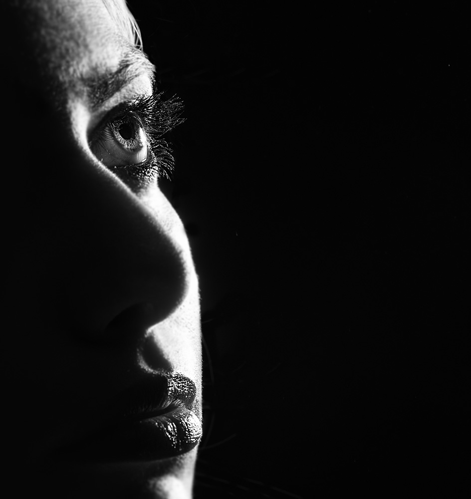 Close up view of a beautiful eye with mascara on and dark lips in black and white.