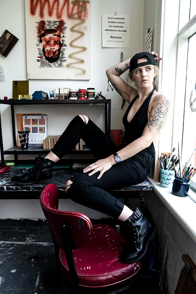 Edge tatted blonde artist sitting sideways on her desk in her messy art studio. Alyssa Bryn Photography. Bryssa. Bryssa Blog.