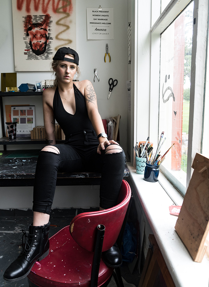 Edge tatted blonde artist sits in her paint splattered desk in her messy art studio. Alyssa Bryn Photography. Bryssa. Bryssa Blog.