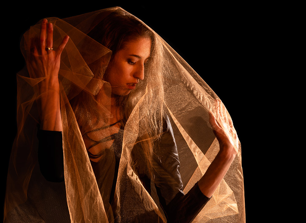 Girl in black leotard throwing around a piece of orange sheer fabric with dramatic side lighting. Alyssa Bryn Photography. Bryssa. Bryssa Blog.