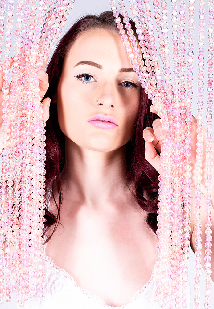 Dark hair blue eyed girl wearing pink lipstick and silver nose ring posing with strands of pink glass beads. Alyssa Bryn Photography. Bryssa. Bryssa Blog.