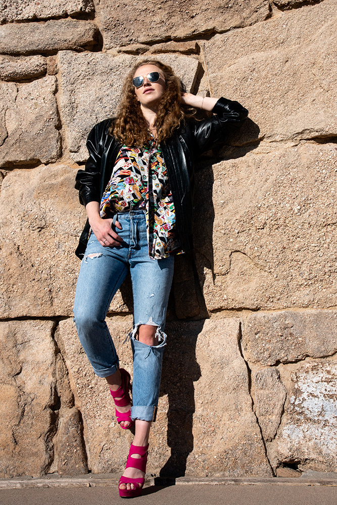 Girl standing by natural rock wall wearing pink high heels, cropped skinny jeans, postcard shirt, black leather jacket and sunglasses. Alyssa Bryn Photography. Bryssa. Bryssa Blog.