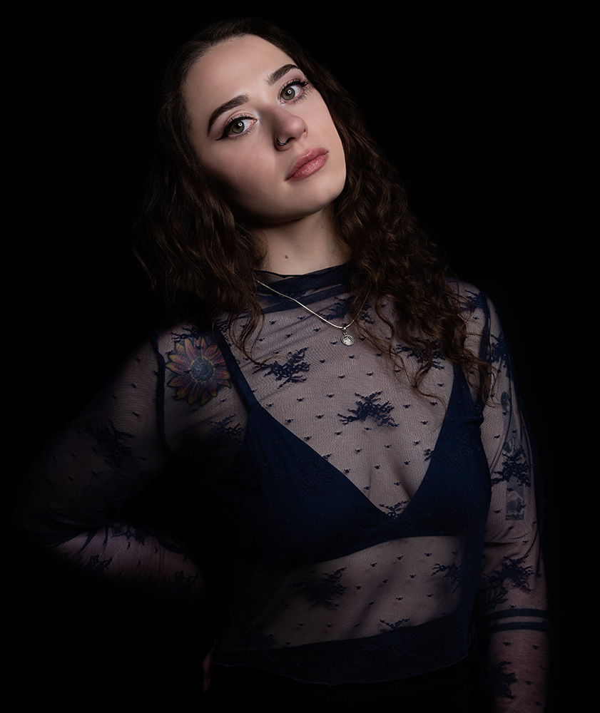 Tattooed girl with long drak curl hair wears sheer midnight blue top with matching dark blue bra under, accessorizing with silver neckless and nose ring. Alyssa Bryn Photography. Bryssa. Bryssa Blog.