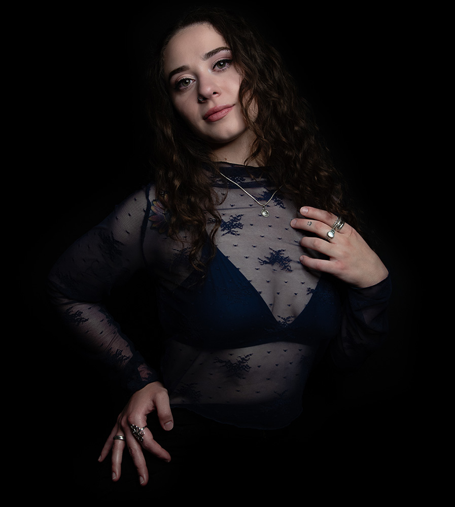 Tattooed girl with long drak curl hair wears sheer midnight blue top with matching dark blue bra under, accessorizing with silver neckless, rings and nose ring. Alyssa Bryn Photography. Bryssa. Bryssa Blog.