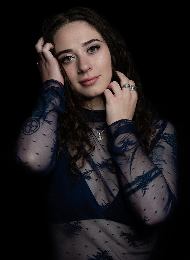 Tattooed girl with long drak curl hair wears sheer midnight blue top with matching dark blue bra under, accessorizing with silver neckless, rings and nose ring. Alyssa Bryn Photography. Bryssa. Bryssa Blog.
