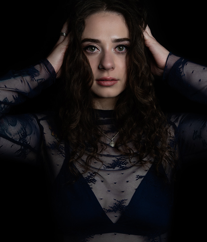 Tattooed girl with long drak curl hair wears sheer midnight blue top with matching dark blue bra under, accessorizing with silver neckless, rings and nose ring. Alyssa Bryn Photography. Bryssa. Bryssa Blog.